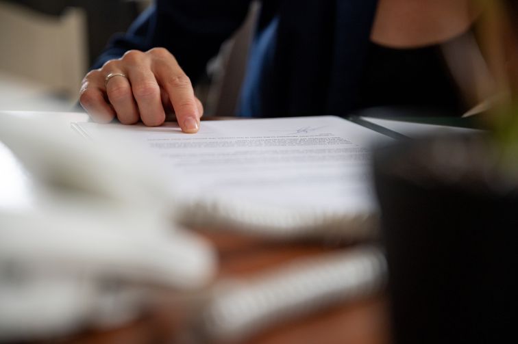 A woman's hand. following down a sheet of paper as she reads