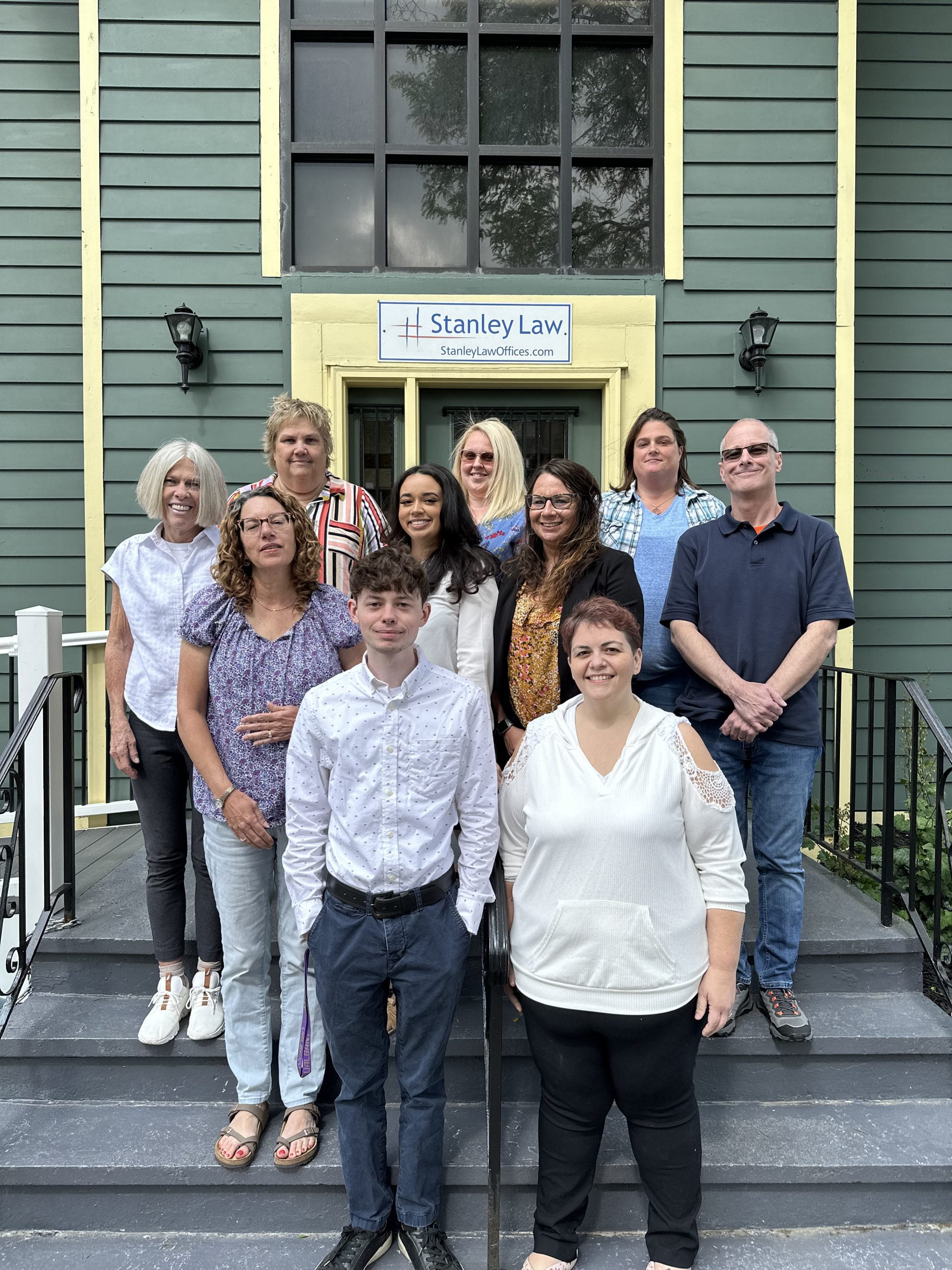 Paralegals of Stanley Law Office standing on Stanley Law offices, steps smiling for their group photo.