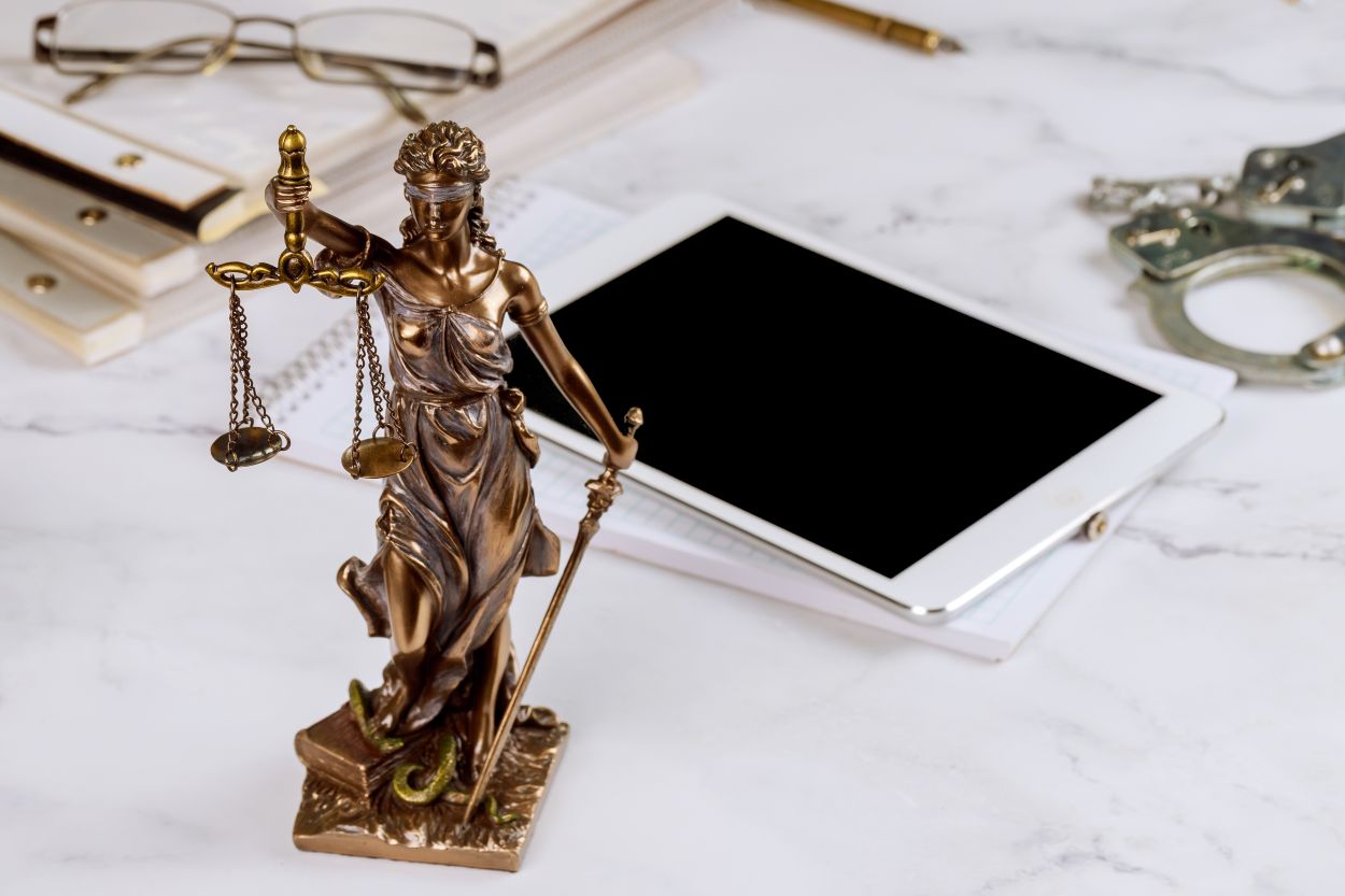 A tablet laying on a marble counter. A bronze statue of blind justice in the. foreground