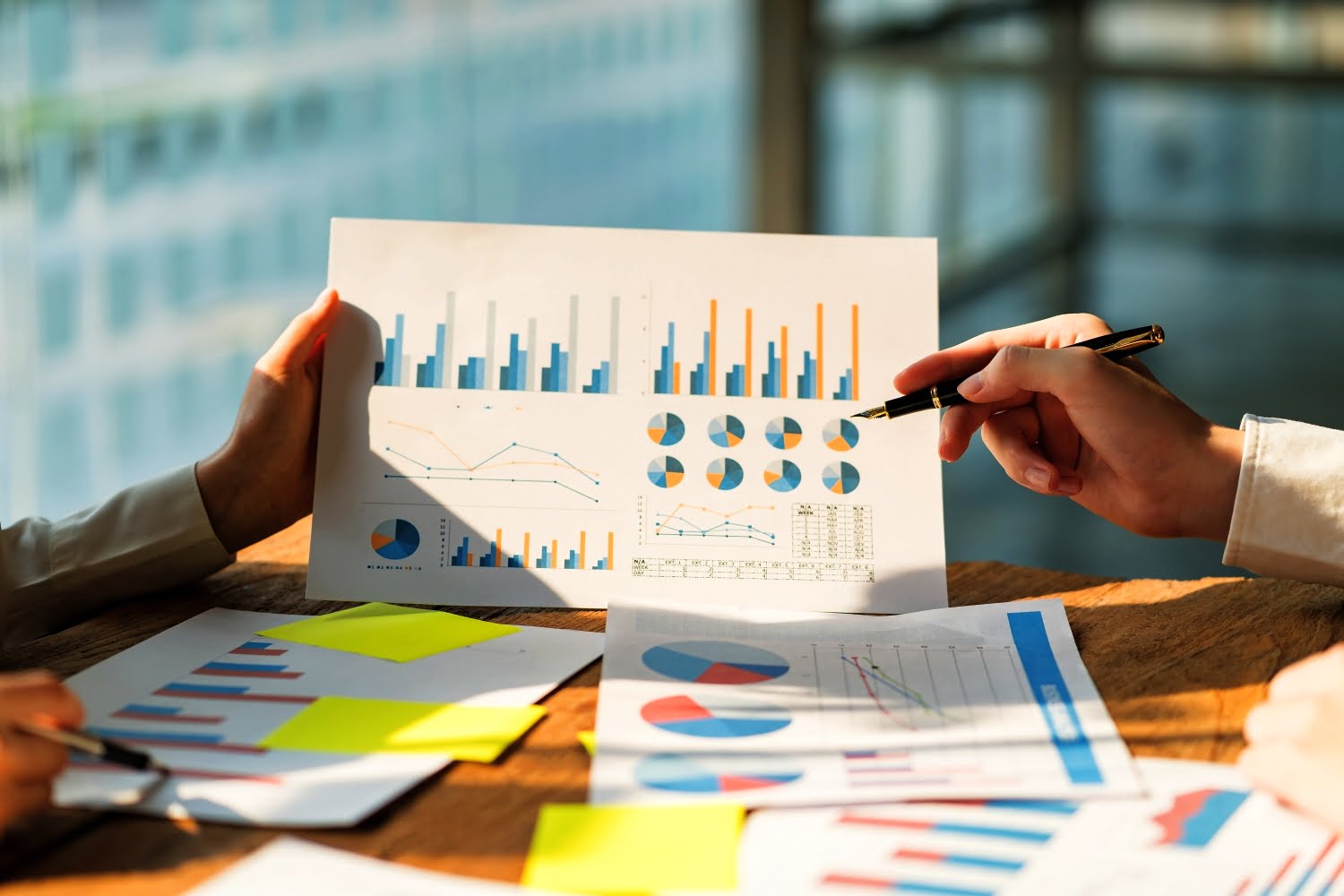 A piece of paper displaying various charts. with two people discussing the content